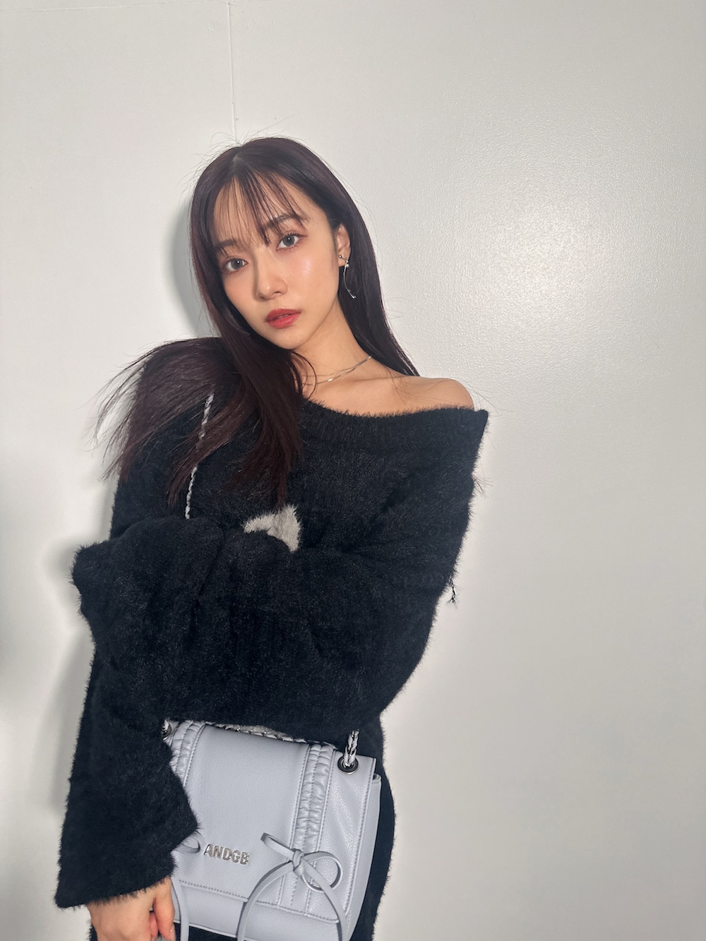 ブラック系のニット/セーター、ブルー系のショルダーバッグを着用したレディースの冬コーディネートの5枚目の写真