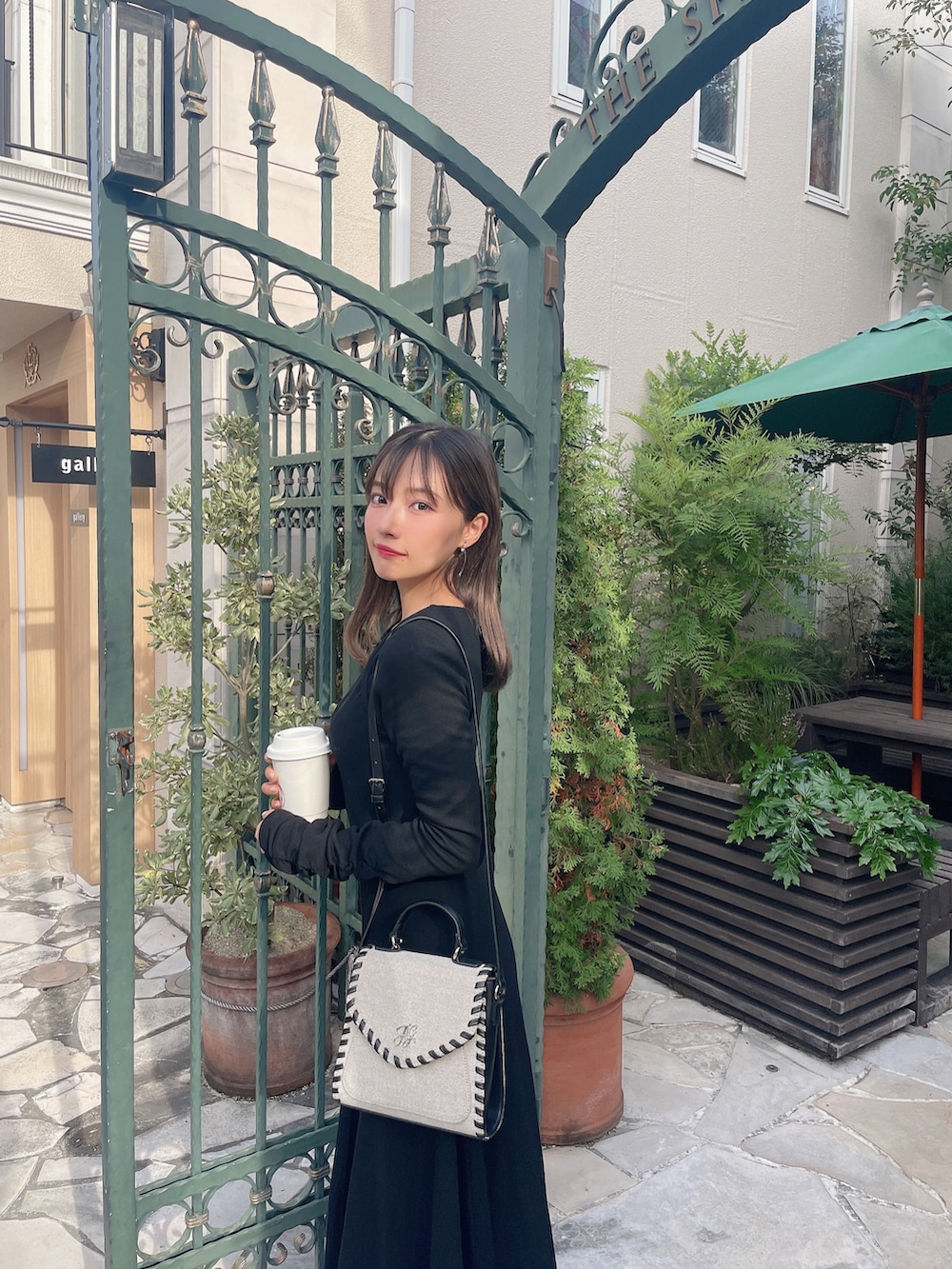 ベージュ系のショルダーバッグ、ブラック系のワンピースを着用したレディースの春コーディネートの2枚目の写真