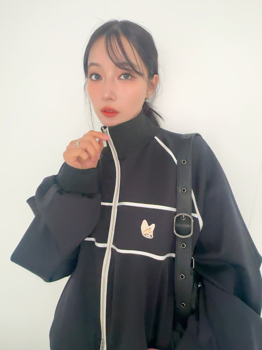 ブラック系のジャージ、ホワイト系のスカート、ブラック系のショルダーバッグを着用したレディースの夏コーディネートの4枚目の写真