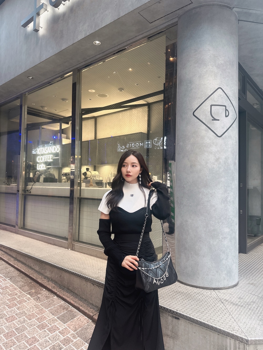 ホワイト系のニット/セーター、ブラック系のスカート、ブラック系のショルダーバッグを着用したレディースの冬コーディネートの3枚目の写真