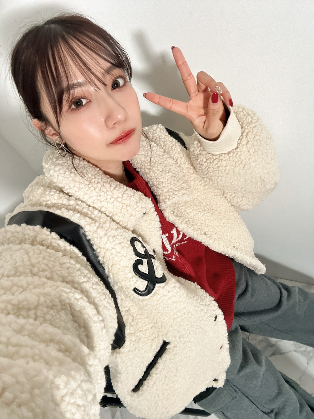 ホワイト系のスタジャン、レッド系のニット/セーター、グレー系のスウェットパンツを着用したレディースの春コーディネートの4枚目の写真