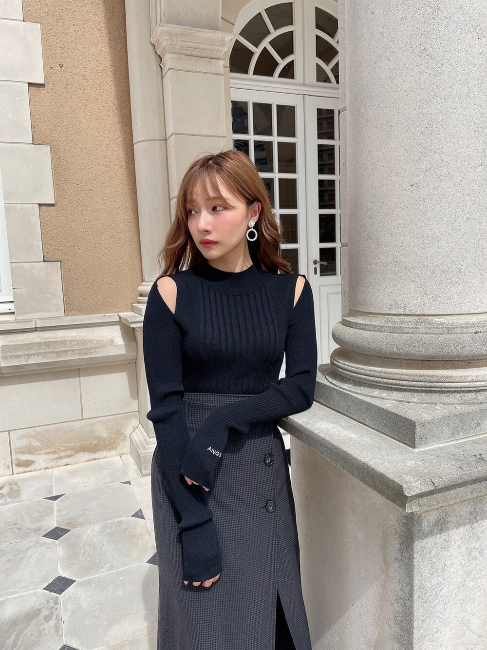 ブラック系のスカート、ブラック系のニット/セーター、ブラック系のブーツを着用したレディースの秋コーディネートの4枚目の写真