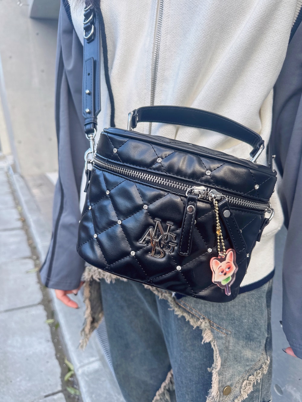 グレー系のベスト、ホワイト系のTシャツ/カットソー、パープル系のショルダーバッグを着用したレディースの夏コーディネートの3枚目の写真