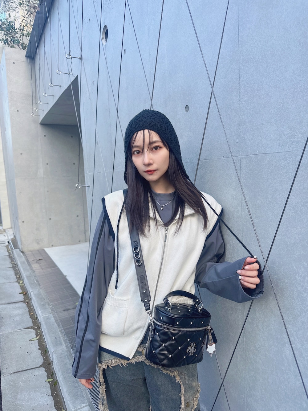 グレー系のベスト、ホワイト系のTシャツ/カットソー、パープル系のショルダーバッグを着用したレディースの夏コーディネートの2枚目の写真