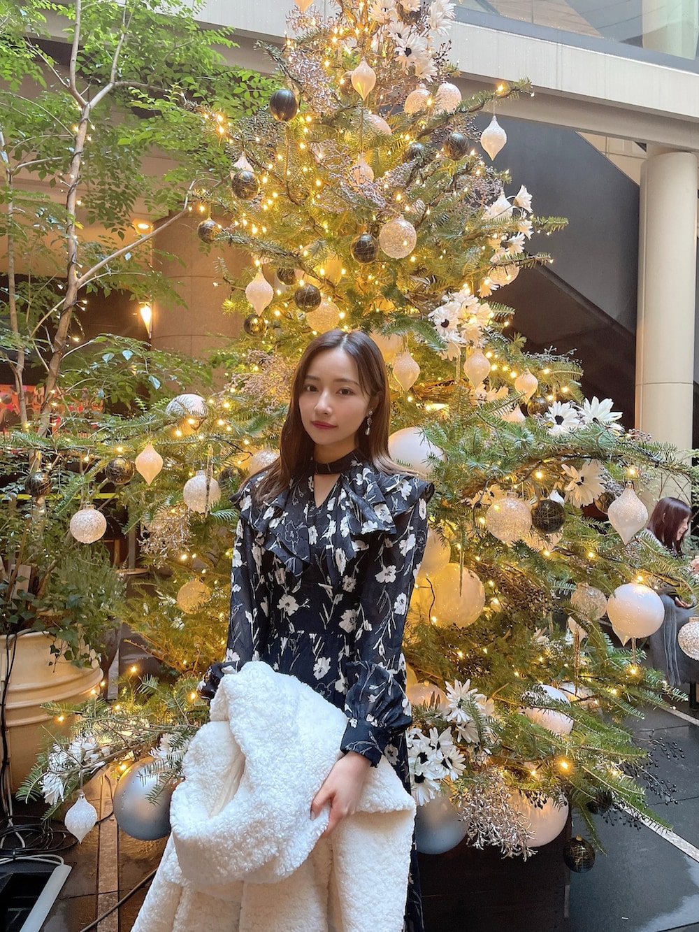 ブラック系のワンピース、ホワイト系のダウンジャケット/コートを着用したレディースの春コーディネートの2枚目の写真