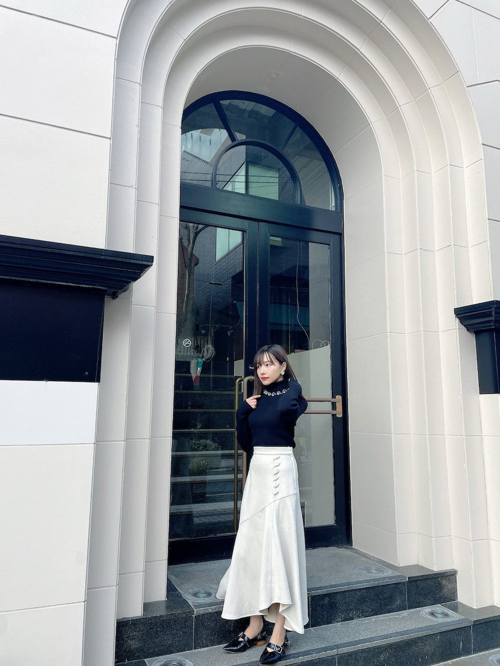 ホワイト系のスカート、ブラック系のニット/セーター、ブラック系のその他シューズを着用したレディースの春コーディネートの2枚目の写真