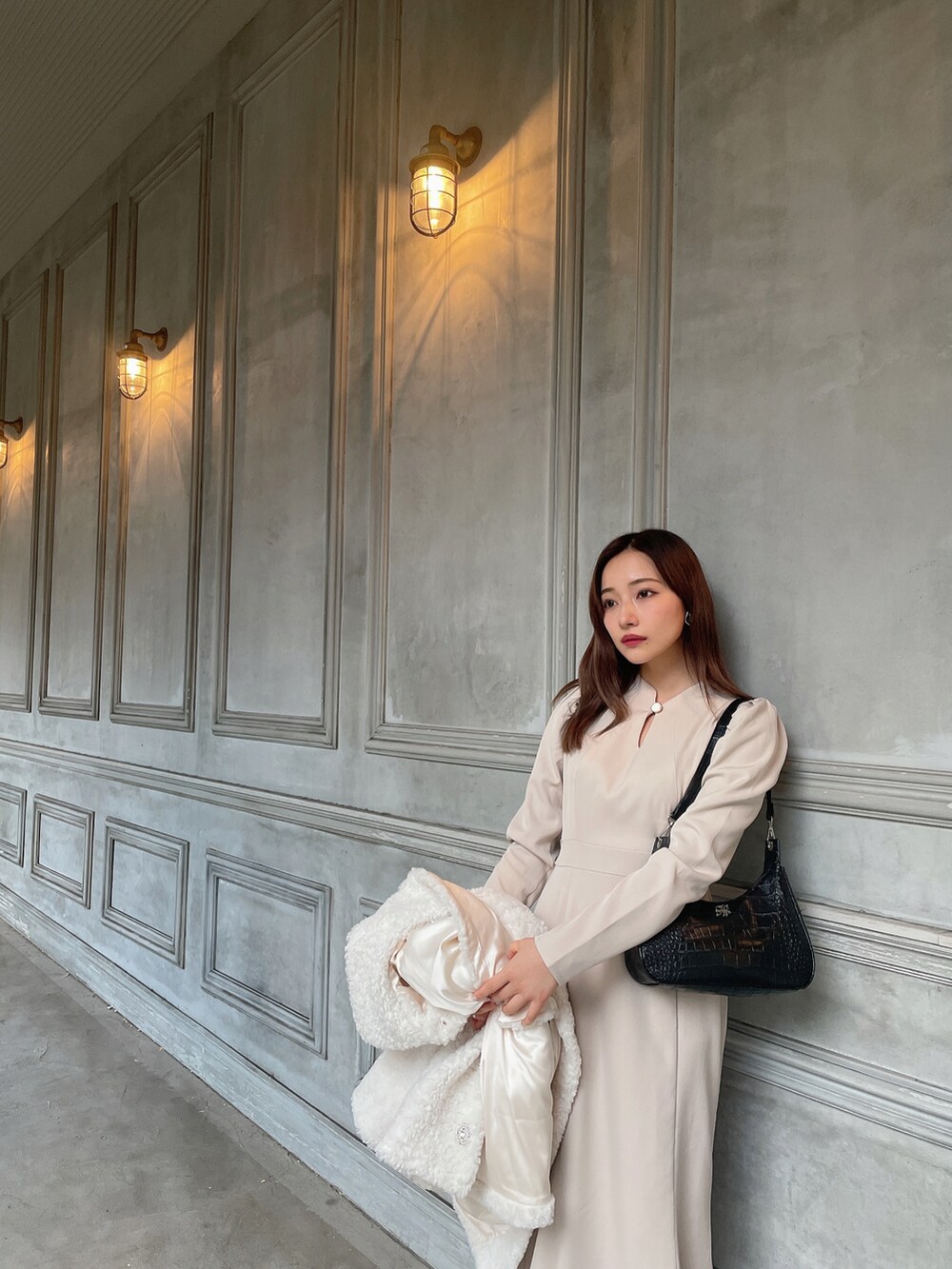 ブラック系のショルダーバッグ、ベージュ系のワンピース、ホワイト系のダウンジャケット/コートを着用したレディースの春コーディネートの4枚目の写真