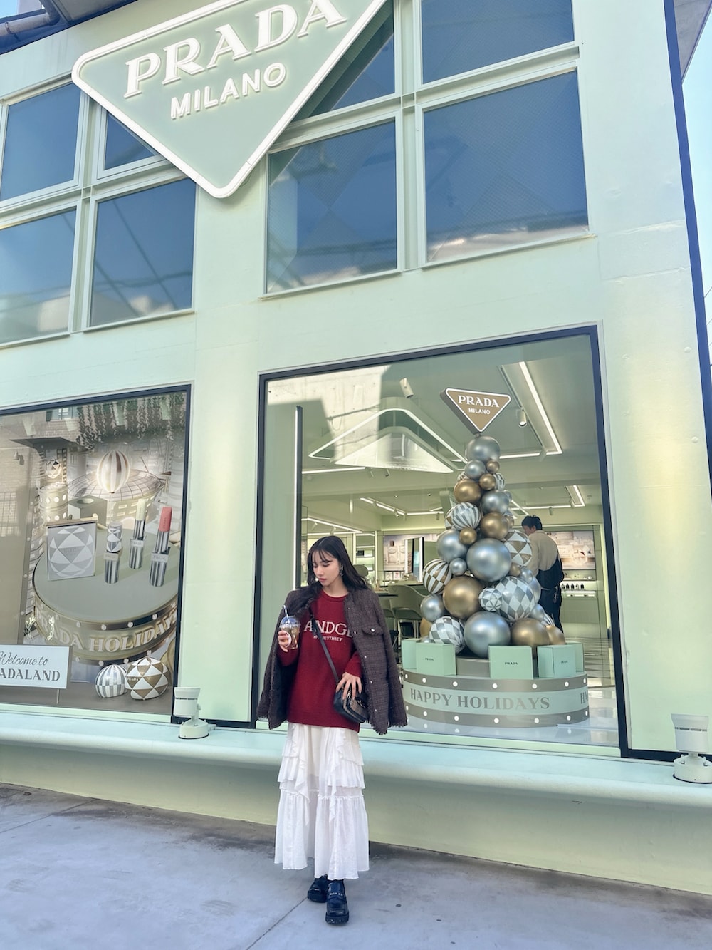 レッド系のニット/セーター、ブラウン系のその他アウター、ホワイト系のスカートを着用したレディースの冬コーディネートの2枚目の写真