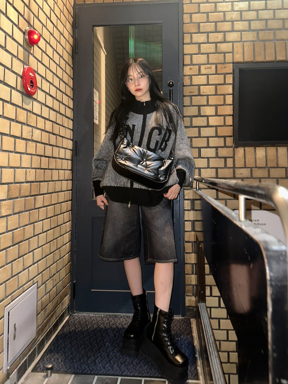 ブラック系のニット/セーター、ホワイト系のショルダーバッグ、ブラック系のデニムパンツを着用したレディースの冬コーディネートの2枚目の写真