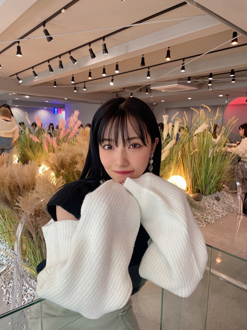 ブラック系のニット/セーター、ホワイト系のスカートを着用したレディースの春コーディネートの2枚目の写真