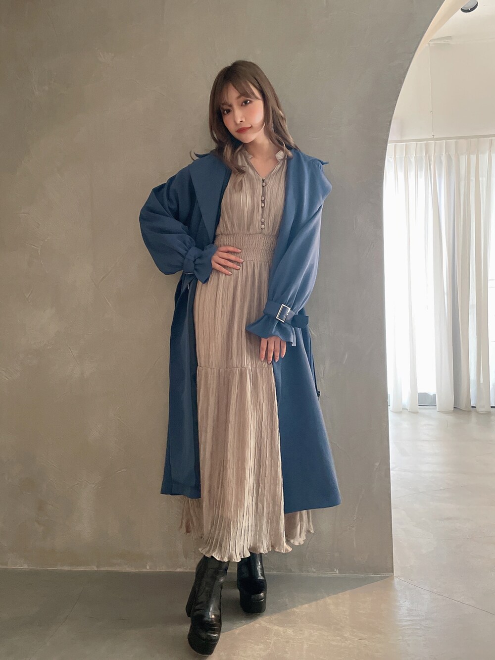 ベージュ系のワンピース、ブラック系のブーツ、グレー系のトレンチコートを着用したレディースの秋コーディネートの3枚目の写真