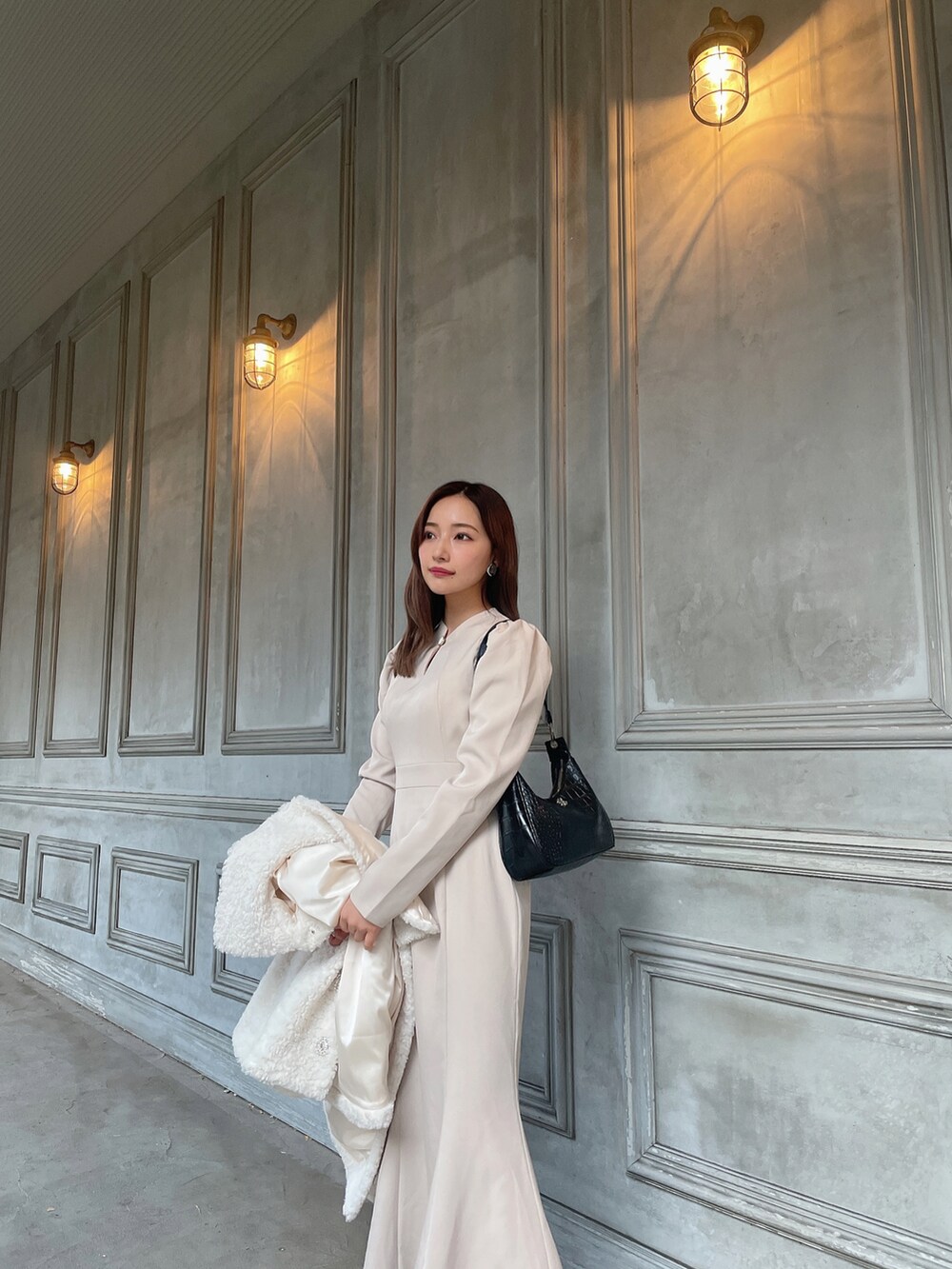 ブラック系のショルダーバッグ、ベージュ系のワンピース、ホワイト系のダウンジャケット/コートを着用したレディースの春コーディネートの2枚目の写真