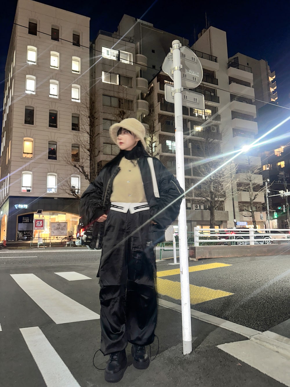 ブラック系のブルゾン、ホワイト系のショルダーバッグ、ブルー系のニット/セーターを着用したレディースの春コーディネートの5枚目の写真