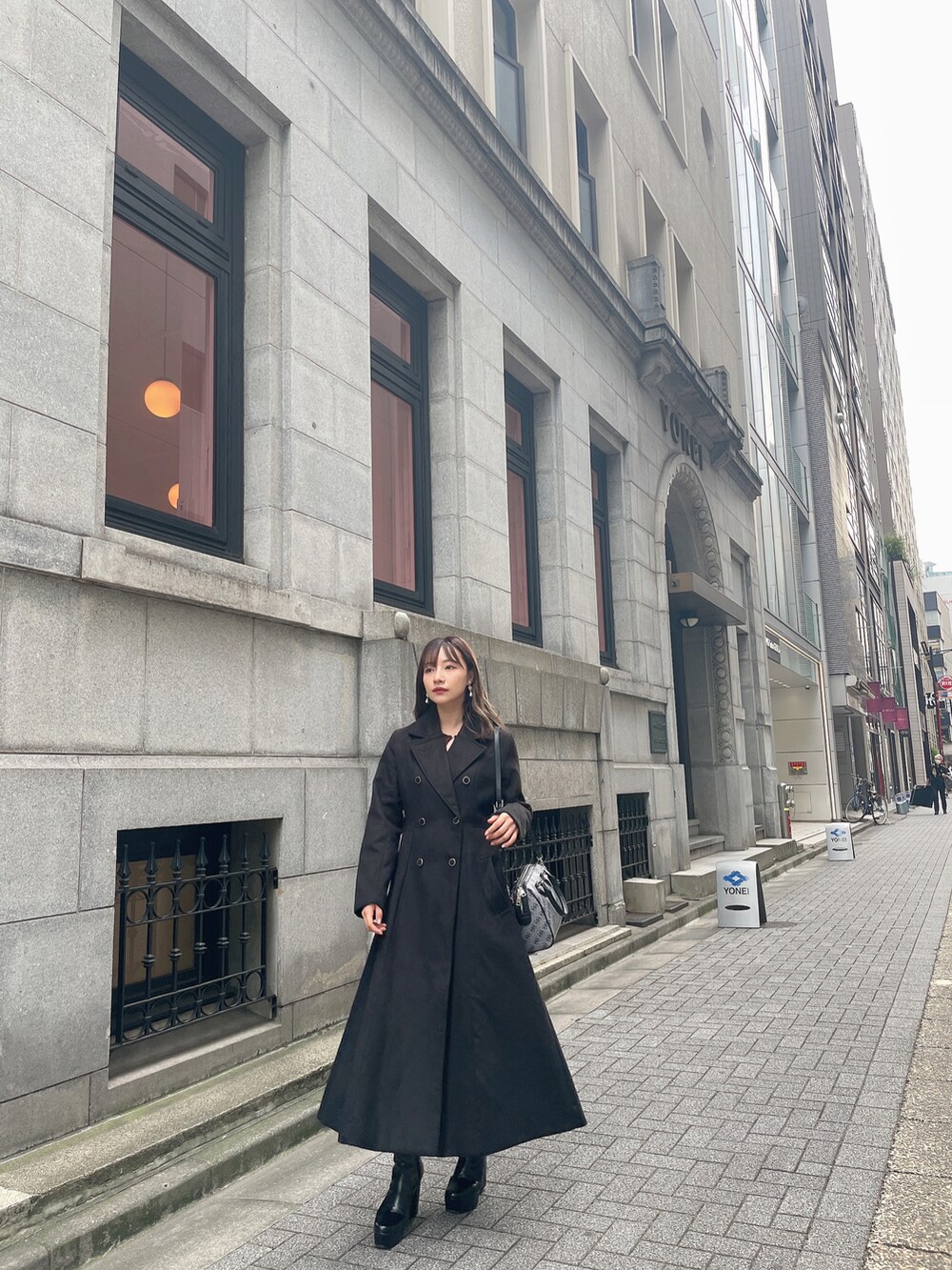 ブラック系のチェスターコート、ブラック系のブーツを着用したレディースの冬コーディネートの3枚目の写真