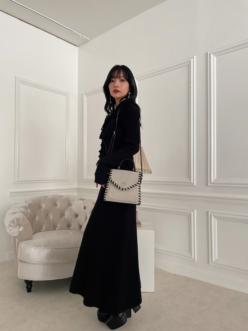 ブラック系のブーツ、ブラック系のワンピース、ベージュ系のショルダーバッグを着用したレディースの冬コーディネートの3枚目の写真