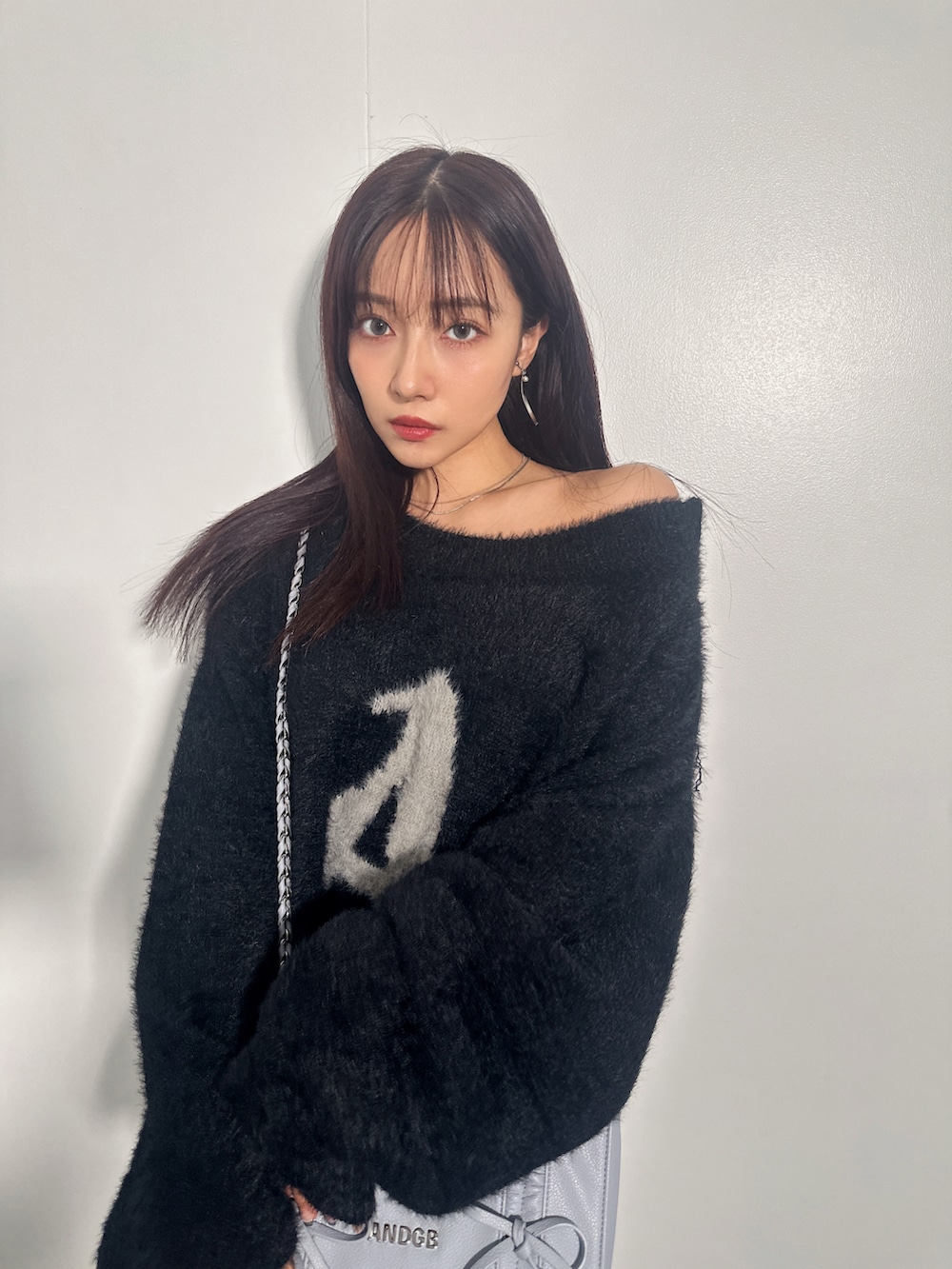 ブラック系のニット/セーター、ブルー系のショルダーバッグを着用したレディースの冬コーディネートの3枚目の写真