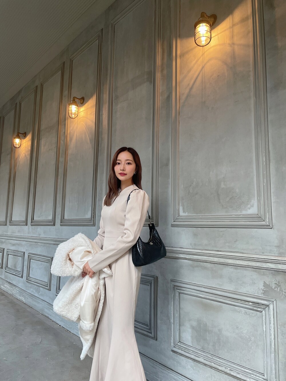 ブラック系のショルダーバッグ、ベージュ系のワンピース、ホワイト系のダウンジャケット/コートを着用したレディースの春コーディネートの3枚目の写真