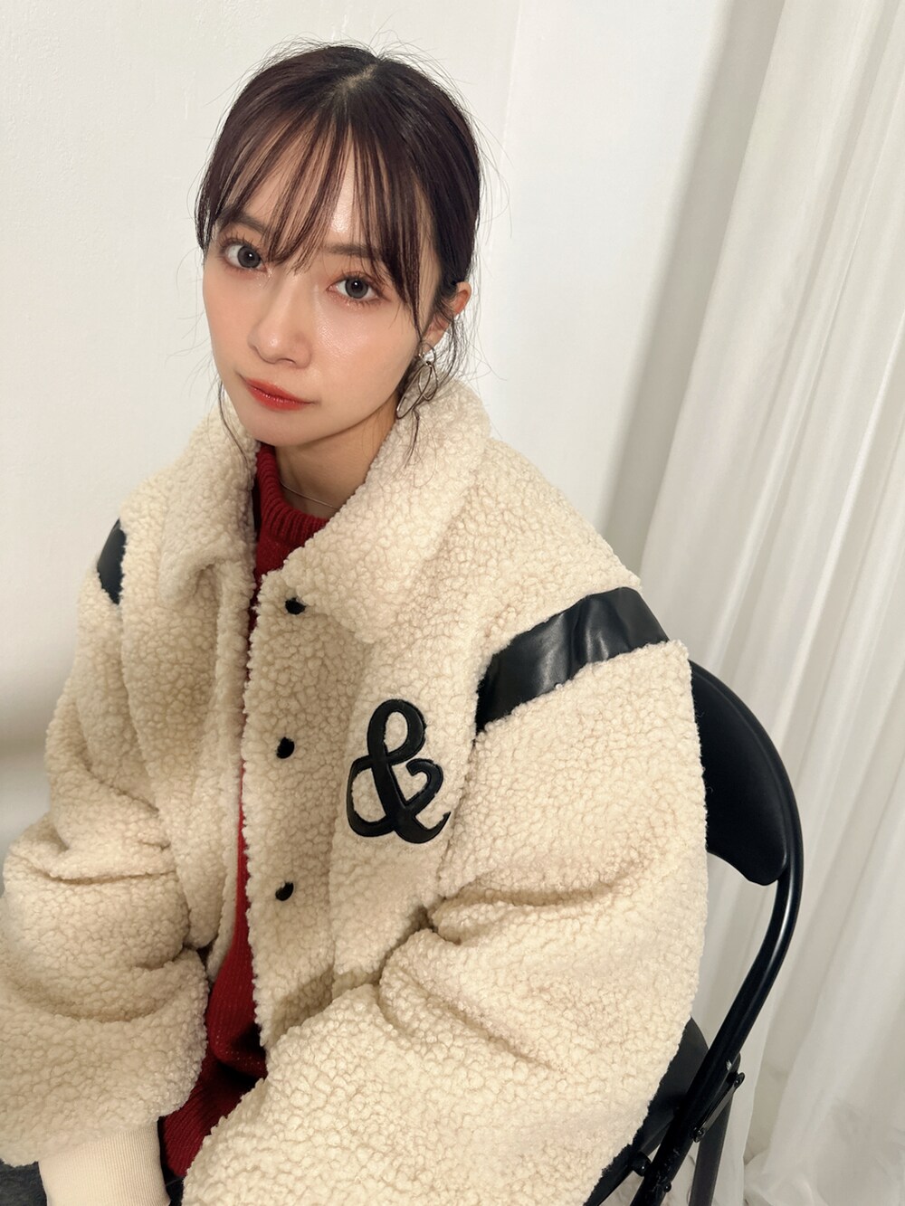 ホワイト系のスタジャン、レッド系のニット/セーター、グレー系のスウェットパンツを着用したレディースの春コーディネートの3枚目の写真