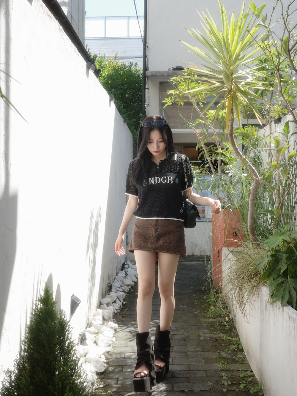 ブラック系のポロシャツ、ブラウン系のスカート、ブラック系のサンダルを着用したレディースの秋コーディネートの3枚目の写真