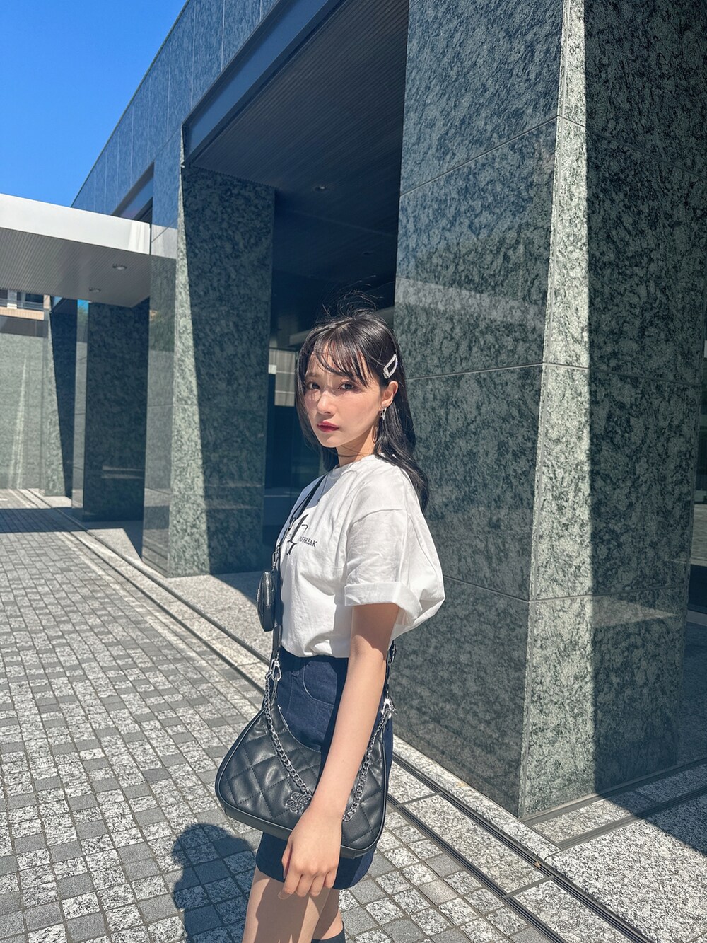 ホワイト系のTシャツ/カットソー、ブラック系のショルダーバッグを着用したレディースの夏コーディネートの2枚目の写真