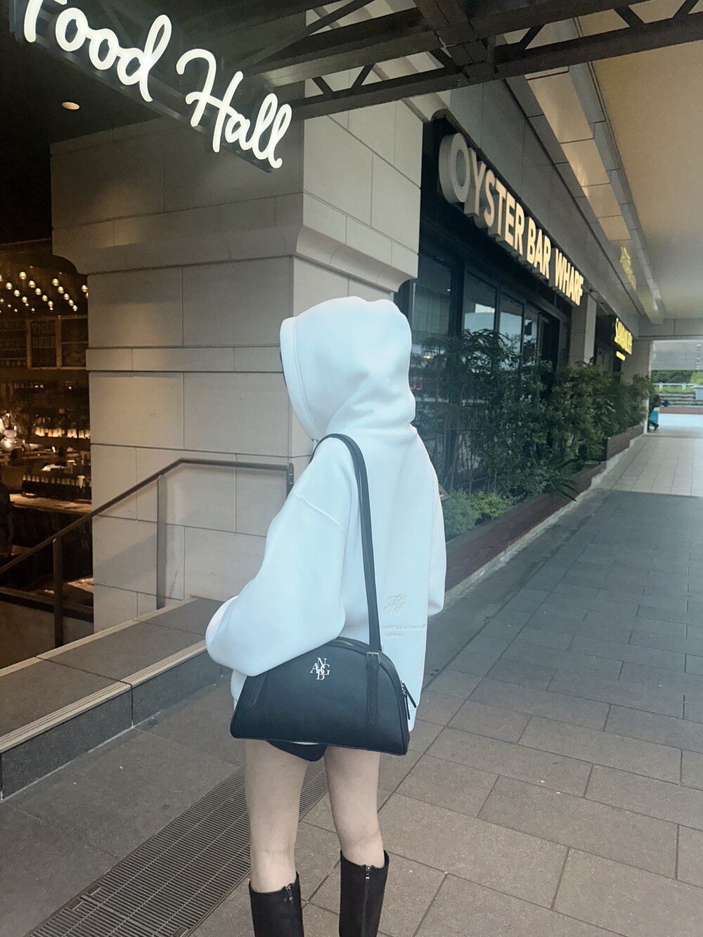 ブラック系のショルダーバッグ、ホワイト系のパーカーを着用したレディースの冬コーディネートの3枚目の写真