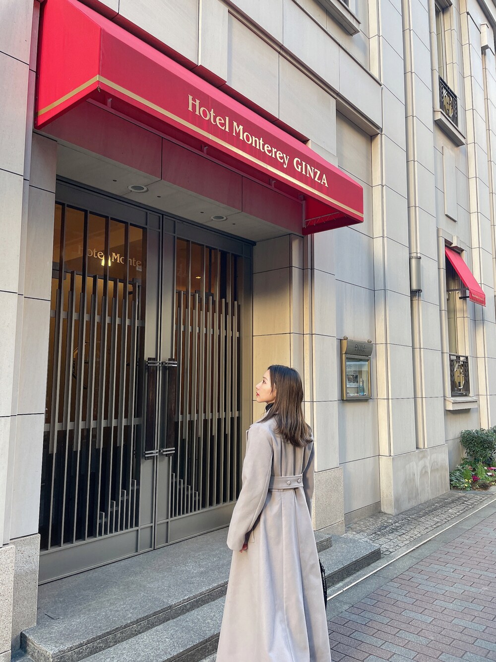 グレー系のチェスターコート、ブラック系のその他シューズ、ベージュ系のショルダーバッグを着用したレディースの春コーディネートの2枚目の写真