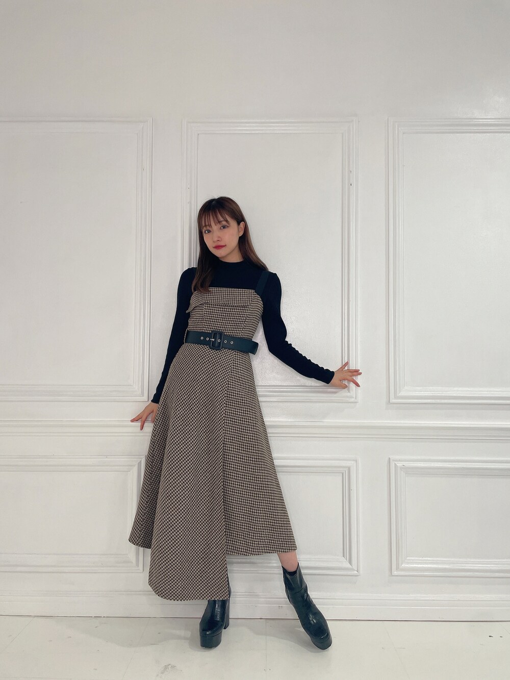 ブラウン系のワンピース、ブラック系のブーツを着用したレディースの冬コーディネートの2枚目の写真