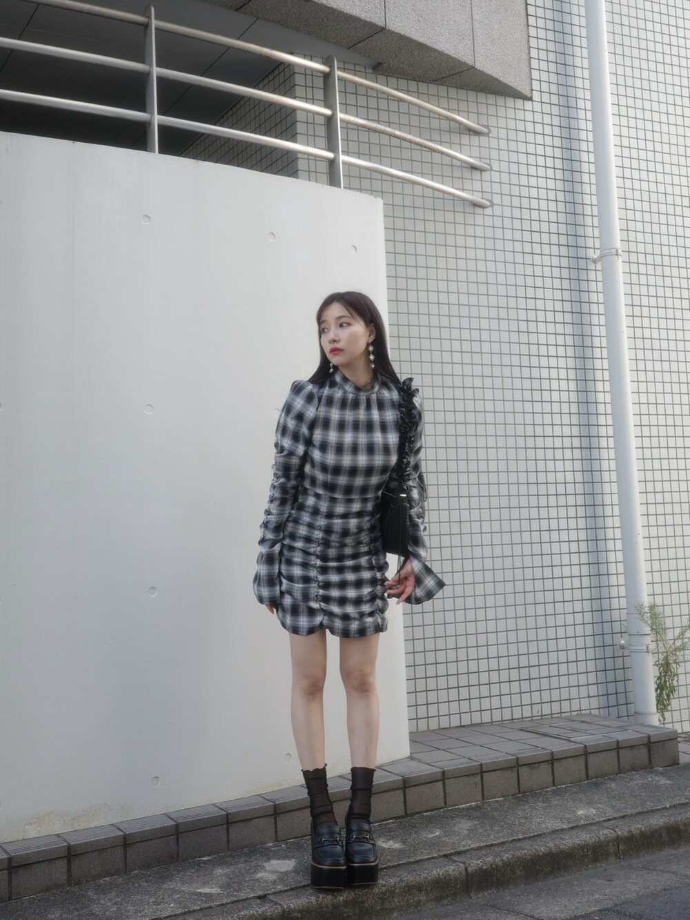 ブラック系のワンピース、ブラック系のローファー、ブラック系のショルダーバッグを着用したレディースの冬コーディネートの5枚目の写真