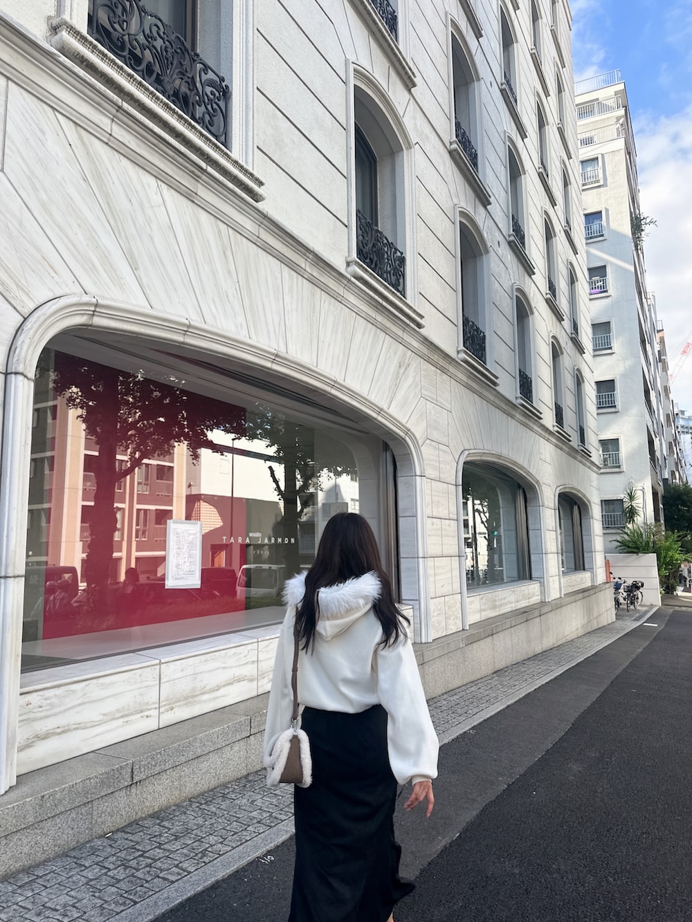 ブラウン系のショルダーバッグ、ホワイト系のパーカー、ブラック系のスカートを着用したレディースの冬コーディネートの4枚目の写真