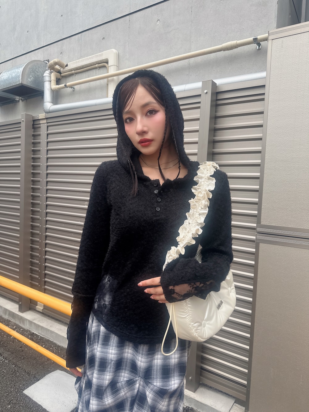 ブラック系のニット/セーター、ブルー系のスカート、ホワイト系のショルダーバッグを着用したレディースの秋コーディネートの4枚目の写真