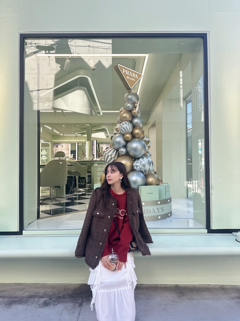 レッド系のニット/セーター、ブラウン系のその他アウター、ホワイト系のスカートを着用したレディースの冬コーディネートの5枚目の写真