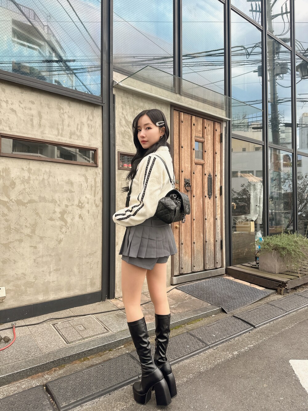 ホワイト系のニット/セーター、ブラック系のバックパック/リュックを着用したレディースの春コーディネートの3枚目の写真