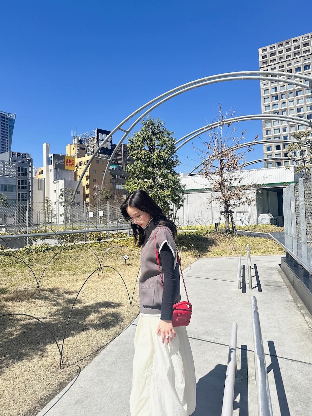 グレー系のベスト、ホワイト系のスカートを着用したレディースの夏コーディネートの2枚目の写真