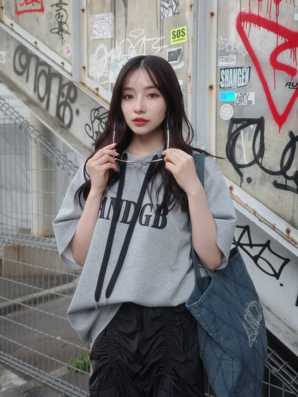 グレー系のパーカー、ブラック系のカーゴパンツ、ブラック系のトートバッグを着用したレディースの秋コーディネートの3枚目の写真