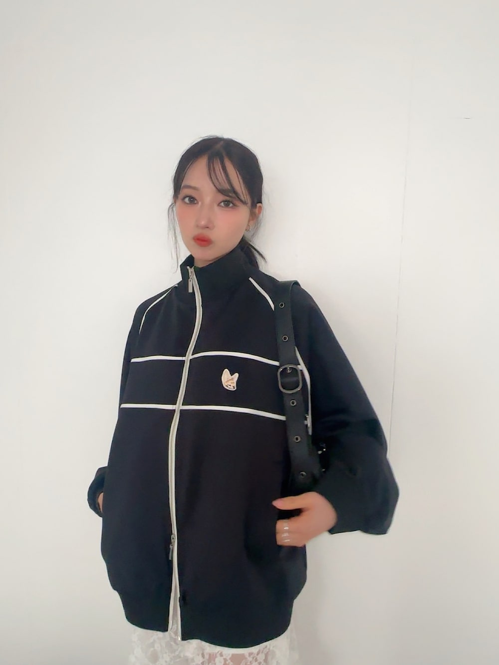 ブラック系のジャージ、ホワイト系のスカート、ブラック系のショルダーバッグを着用したレディースの夏コーディネートの3枚目の写真