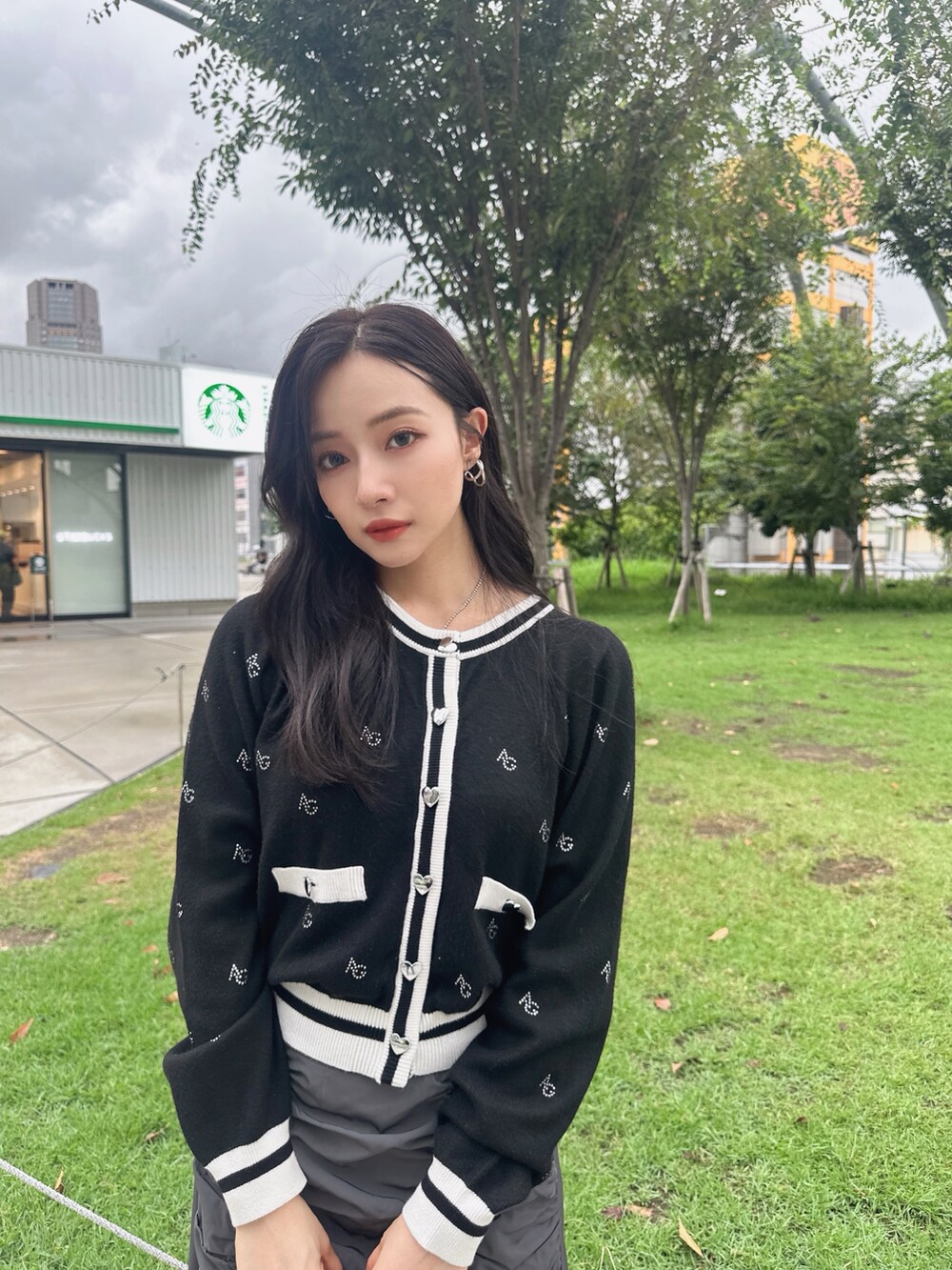 グレー系のスカート、ホワイト系のアンサンブルを着用したレディースの秋コーディネートの2枚目の写真