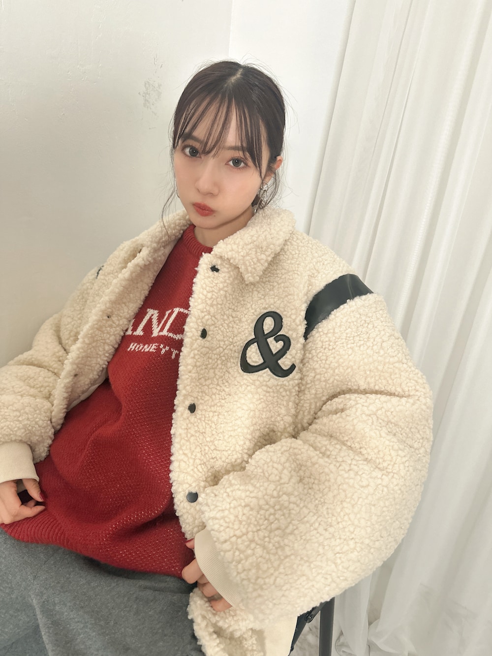 ホワイト系のスタジャン、レッド系のニット/セーター、グレー系のスウェットパンツを着用したレディースの春コーディネートの2枚目の写真