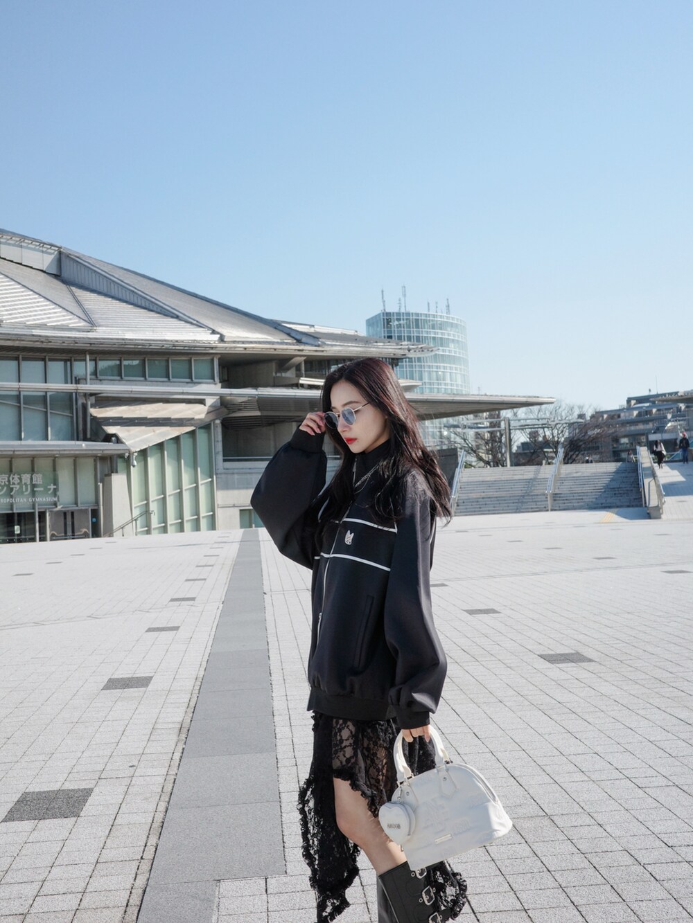 ブラック系のジャージ、ブラック系のスカート、グレー系のショルダーバッグを着用したレディースの夏コーディネートの2枚目の写真