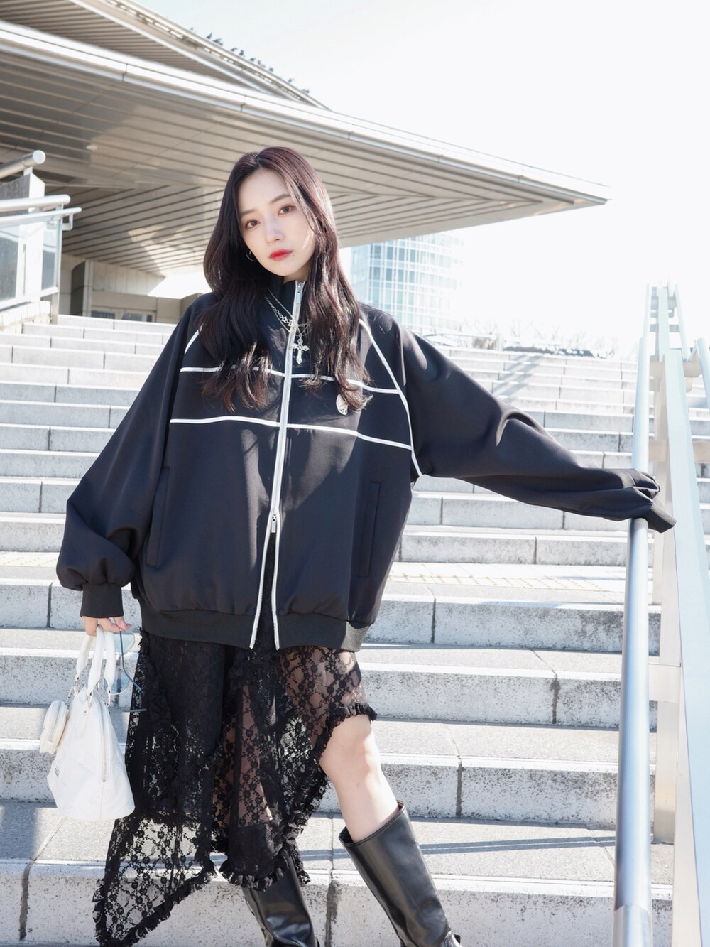 ブラック系のジャージ、ブラック系のスカート、グレー系のショルダーバッグを着用したレディースの夏コーディネートの4枚目の写真