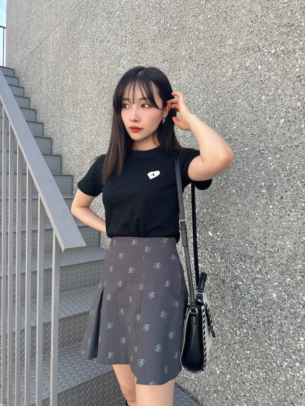 ブラック系のTシャツ/カットソー、グレー系のスカート、ベージュ系のショルダーバッグを着用したレディースの夏コーディネートの2枚目の写真