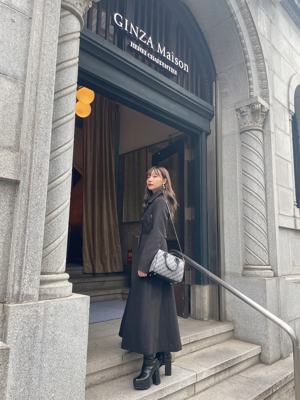 ブラック系のチェスターコート、ブラック系のブーツを着用したレディースの冬コーディネートの2枚目の写真