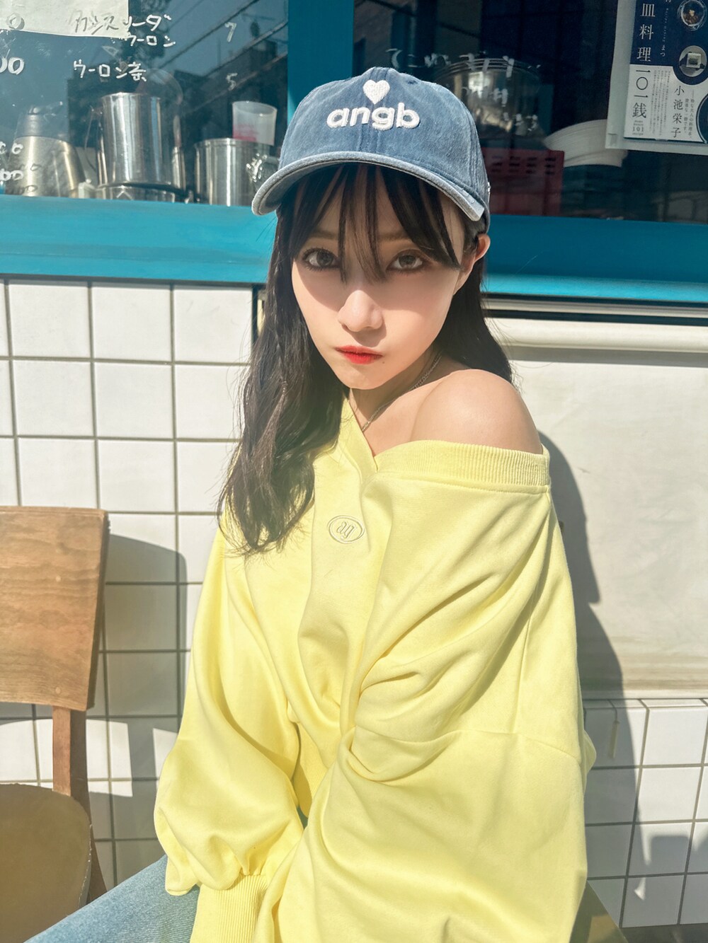 イエロー系のスウェット、ブルー系のキャップを着用したレディースの夏コーディネートの3枚目の写真
