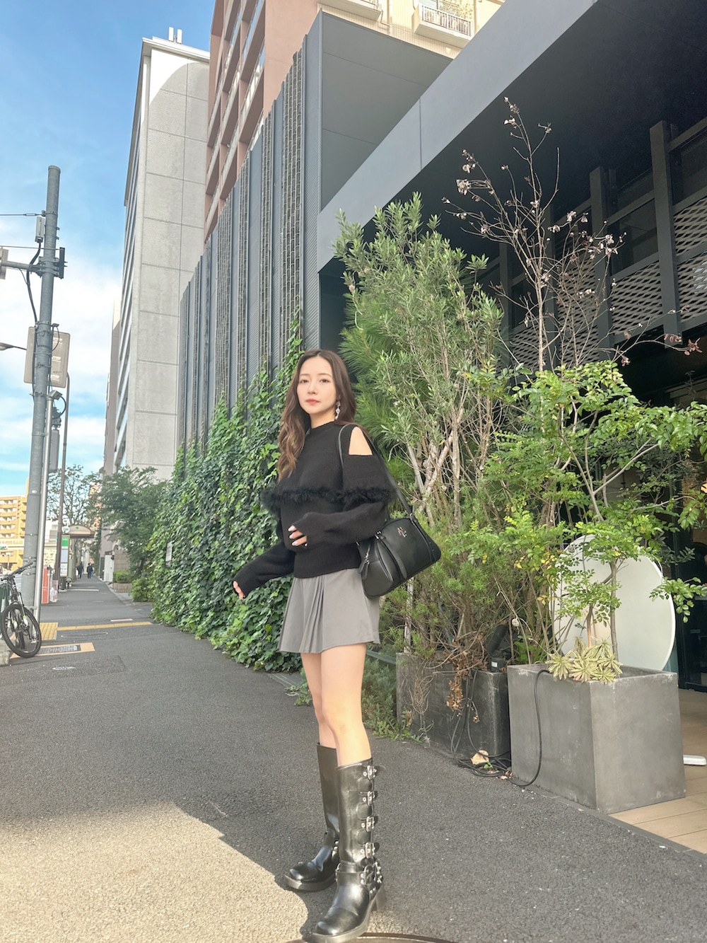 ブラック系のニット/セーター、ブラック系のショルダーバッグを着用したレディースの春コーディネートの2枚目の写真