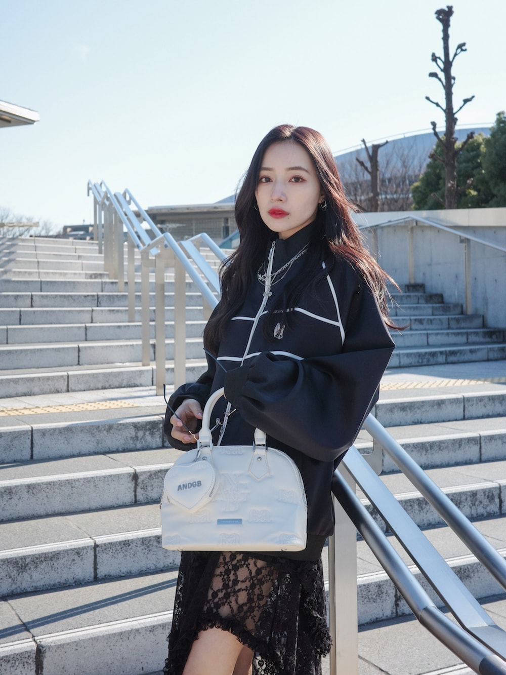 ブラック系のジャージ、ブラック系のスカート、グレー系のショルダーバッグを着用したレディースの夏コーディネートの3枚目の写真