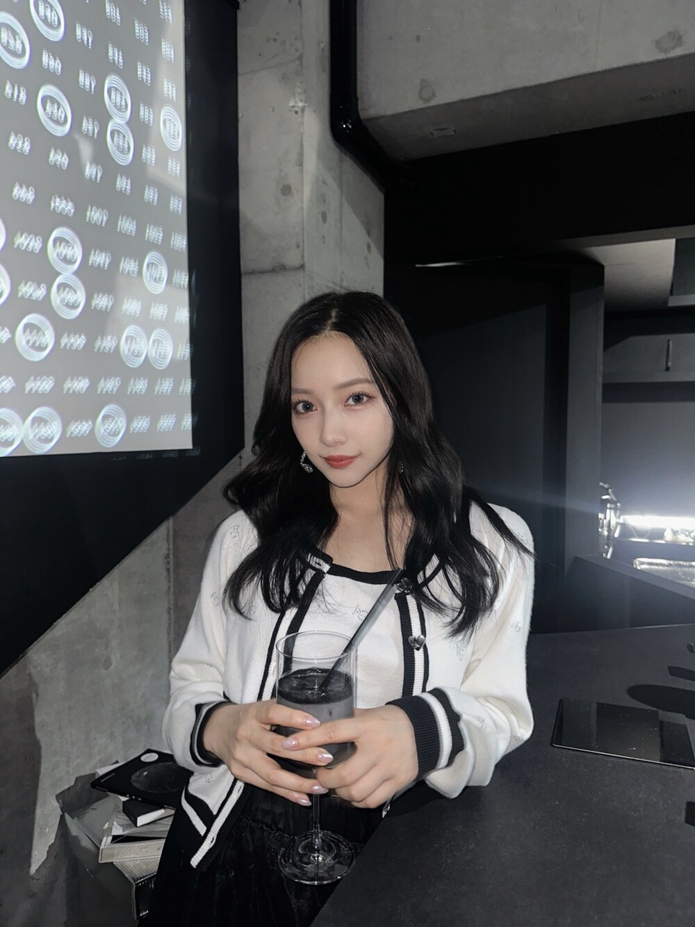 ホワイト系のアンサンブル、グレー系のショルダーバッグ、ブラック系のスカートを着用したレディースの秋コーディネートの2枚目の写真