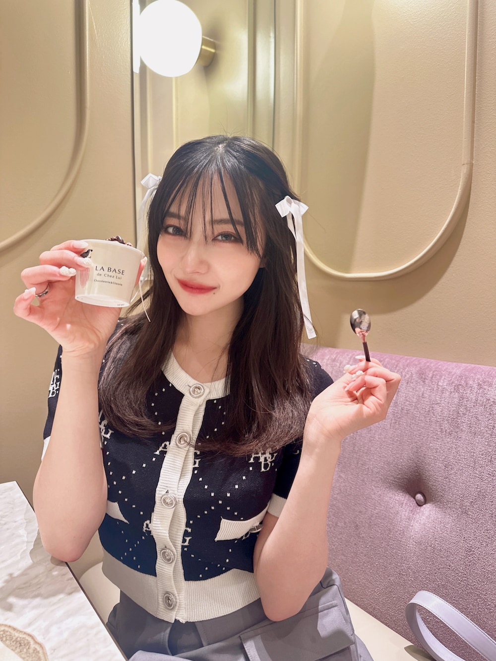 ブラック系のニット/セーター、グレー系のスカート、パープル系のショルダーバッグを着用したレディースの夏コーディネートの2枚目の写真