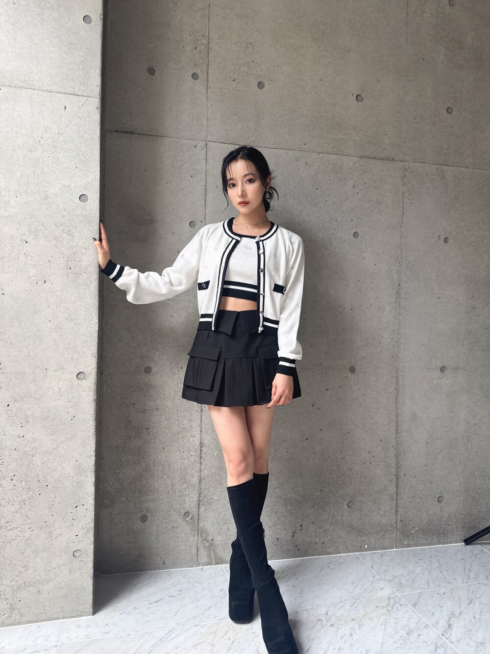 ホワイト系のアンサンブル、ブラック系のスカートを着用したレディースの秋コーディネートの3枚目の写真