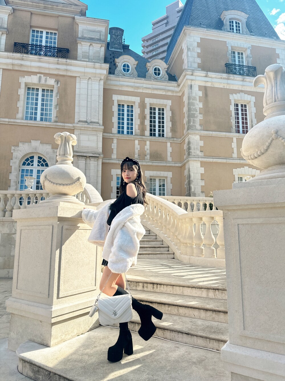 ブラック系のニット/セーター、ホワイト系のその他アウターを着用したレディースの春コーディネートの3枚目の写真