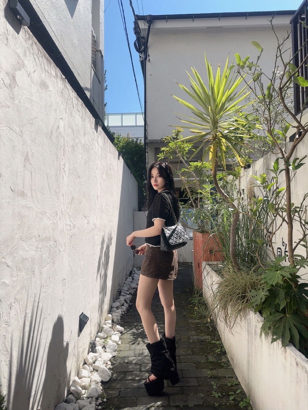 ブラック系のポロシャツ、ブラウン系のスカート、ブラック系のサンダルを着用したレディースの秋コーディネートの5枚目の写真