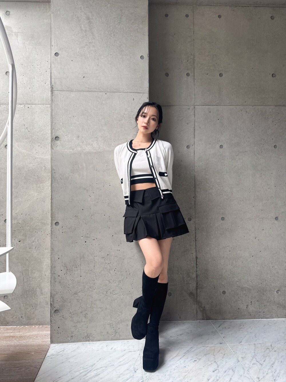 ホワイト系のアンサンブル、ブラック系のスカートを着用したレディースの秋コーディネートの2枚目の写真